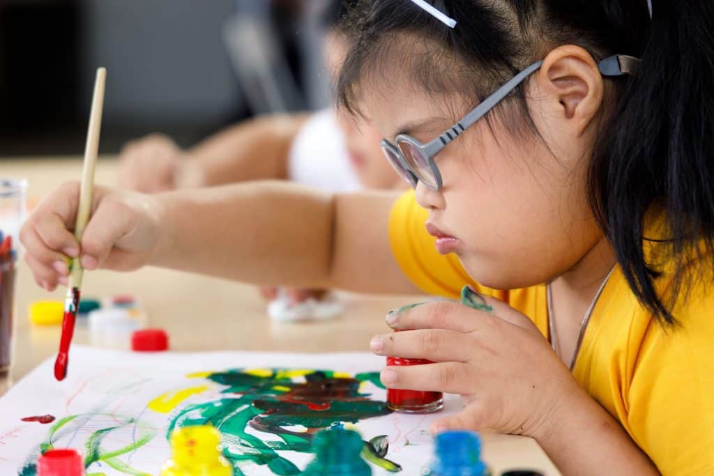 Child with additional support needs making a painting.