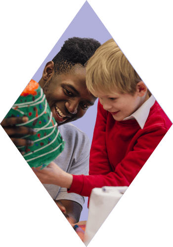 male teacher helps key stage 2 child with their craft project