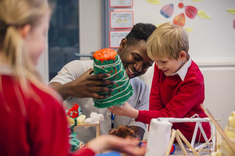 a primary school teacher helps a pupil to complete an activity